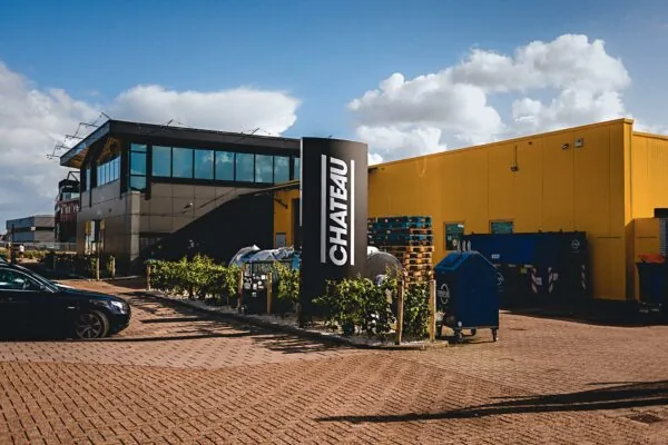 Bedrijfsgebouw en parkeerterrein aan de Johan van Hasseltweg met een zwart CHATEAU-bord en gele gevel.